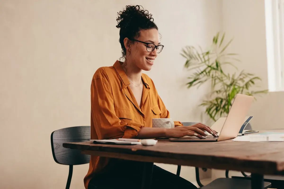 Woman working on laptop computer at home. Woman sitting at table with a coffee cup using a laptop at home office. Woman working on laptop computer at home. Woman sitting at table with a coffee cup using a laptop at home office.